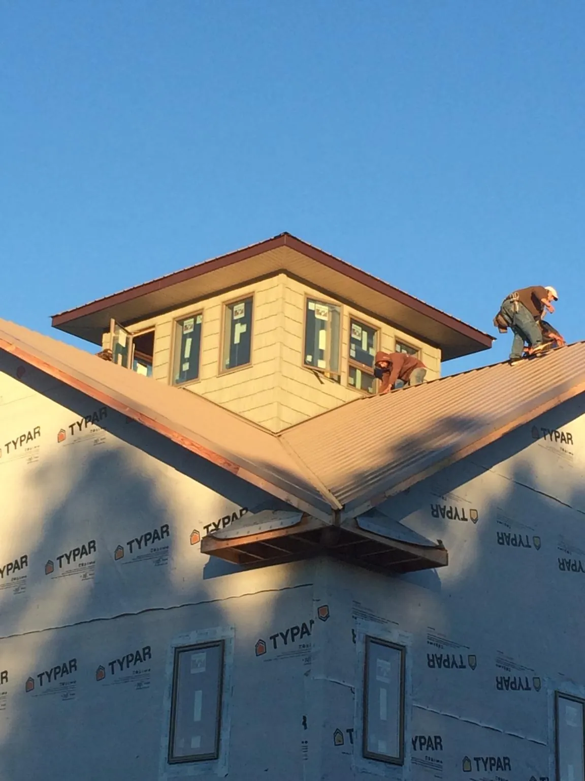 Roofers working around a rooftop cupola on a new metal roof at sunset — Roof Waterproofing in Greenfield by Roofing Brothers